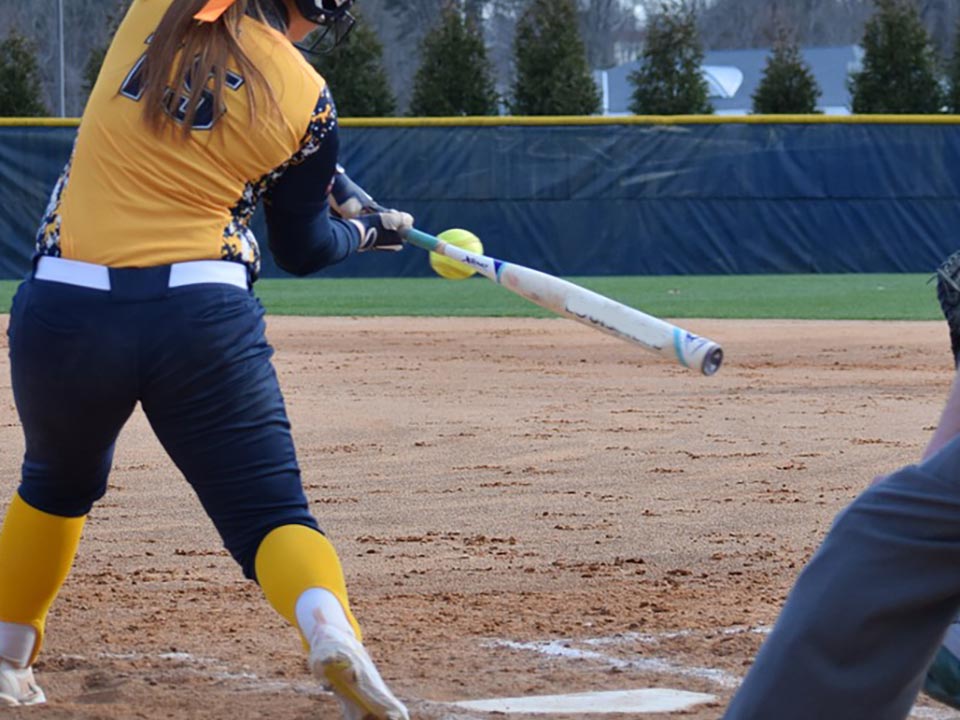 a softball player swinging a bat at a softball