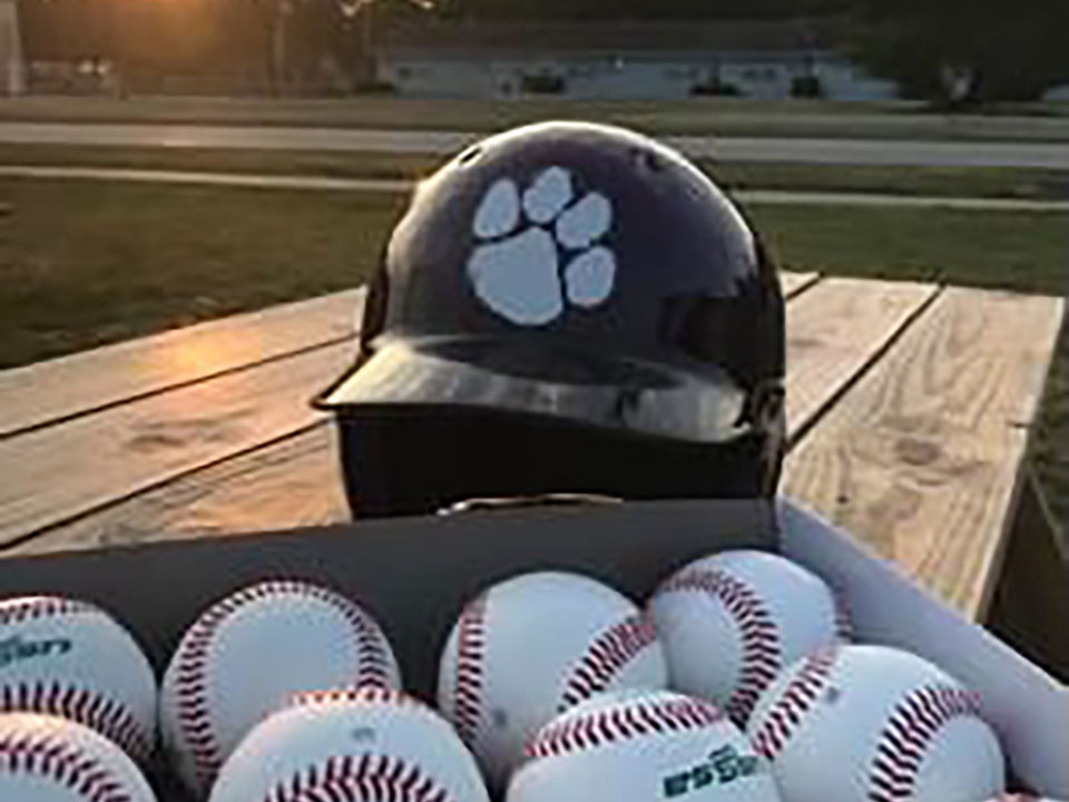 a box of baseballs sitting in front of a batting helmet